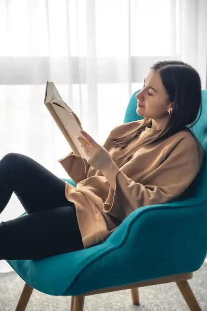 Young woman is reading book while sitting armchair by window 169016 26430